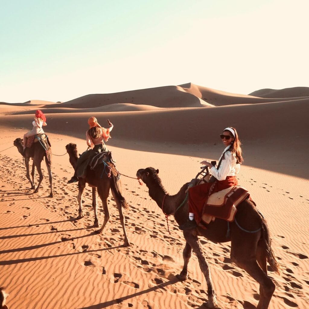 Viajeros sonrientes en un paseo en dromedario por las dunas del Sáhara