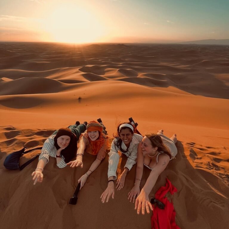 Cuatro amigas tumbadas en la cresta de una duna del Sáhara al atardecer