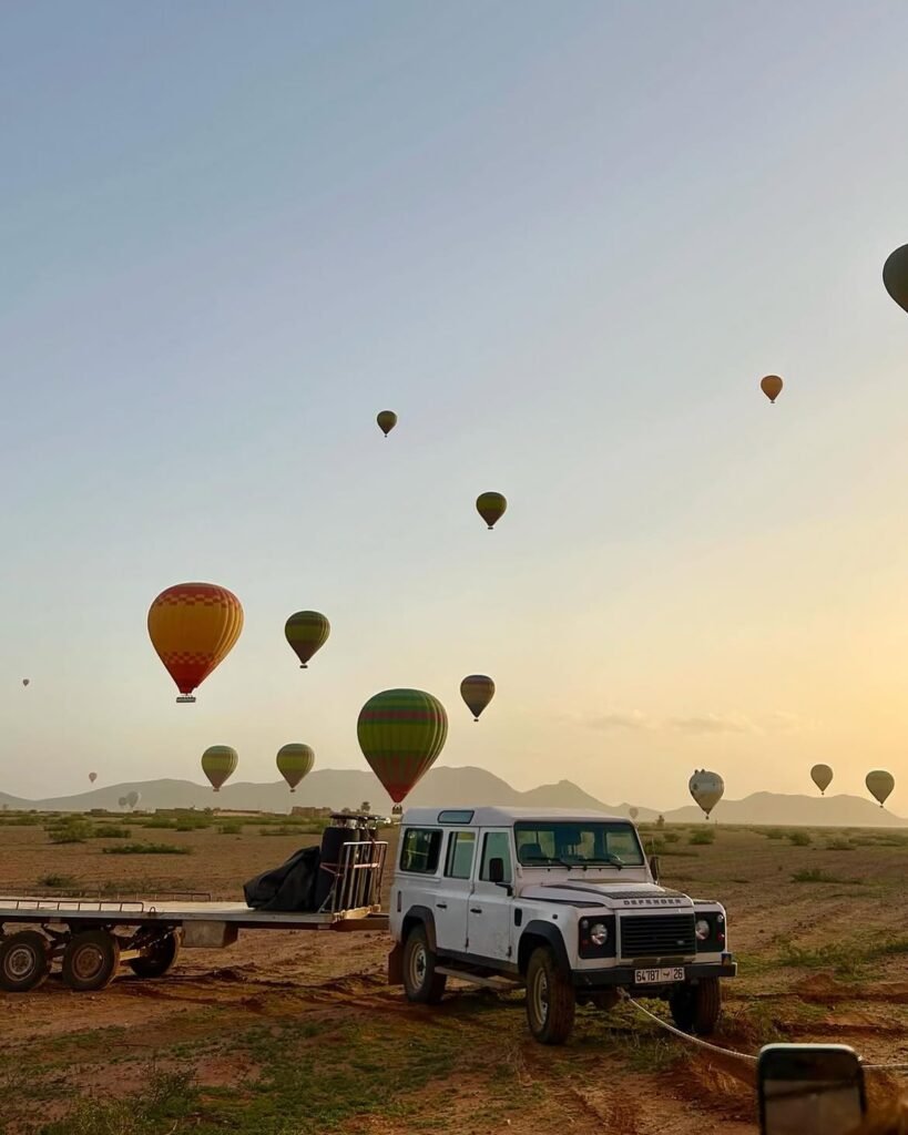 Globos aerostáticos elevándose al amanecer cerca de Marrakech, con un 4x4 de apoyo